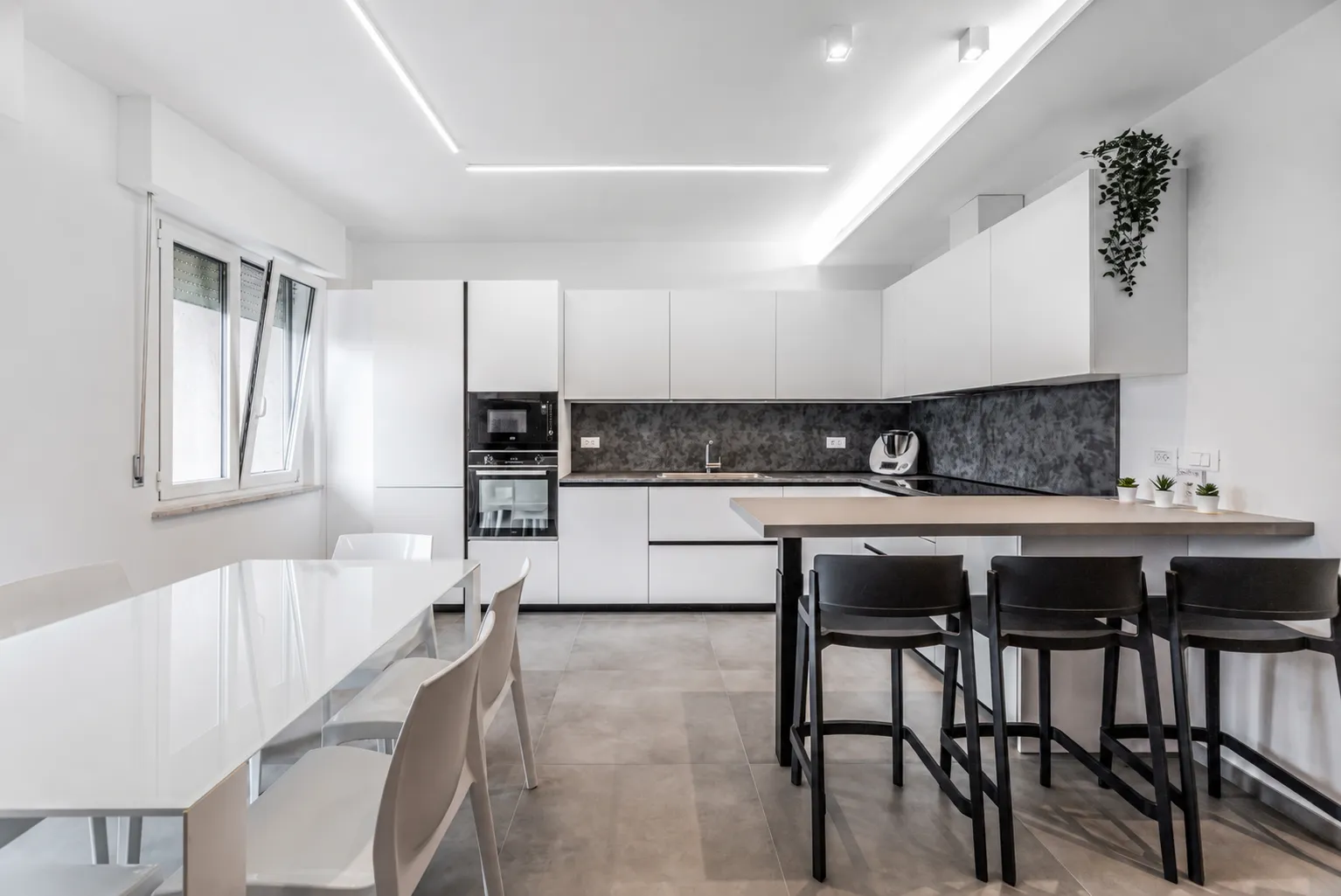 Cucina bianca con penisola e paraschizzi scuro in un appartamento ad Albaro