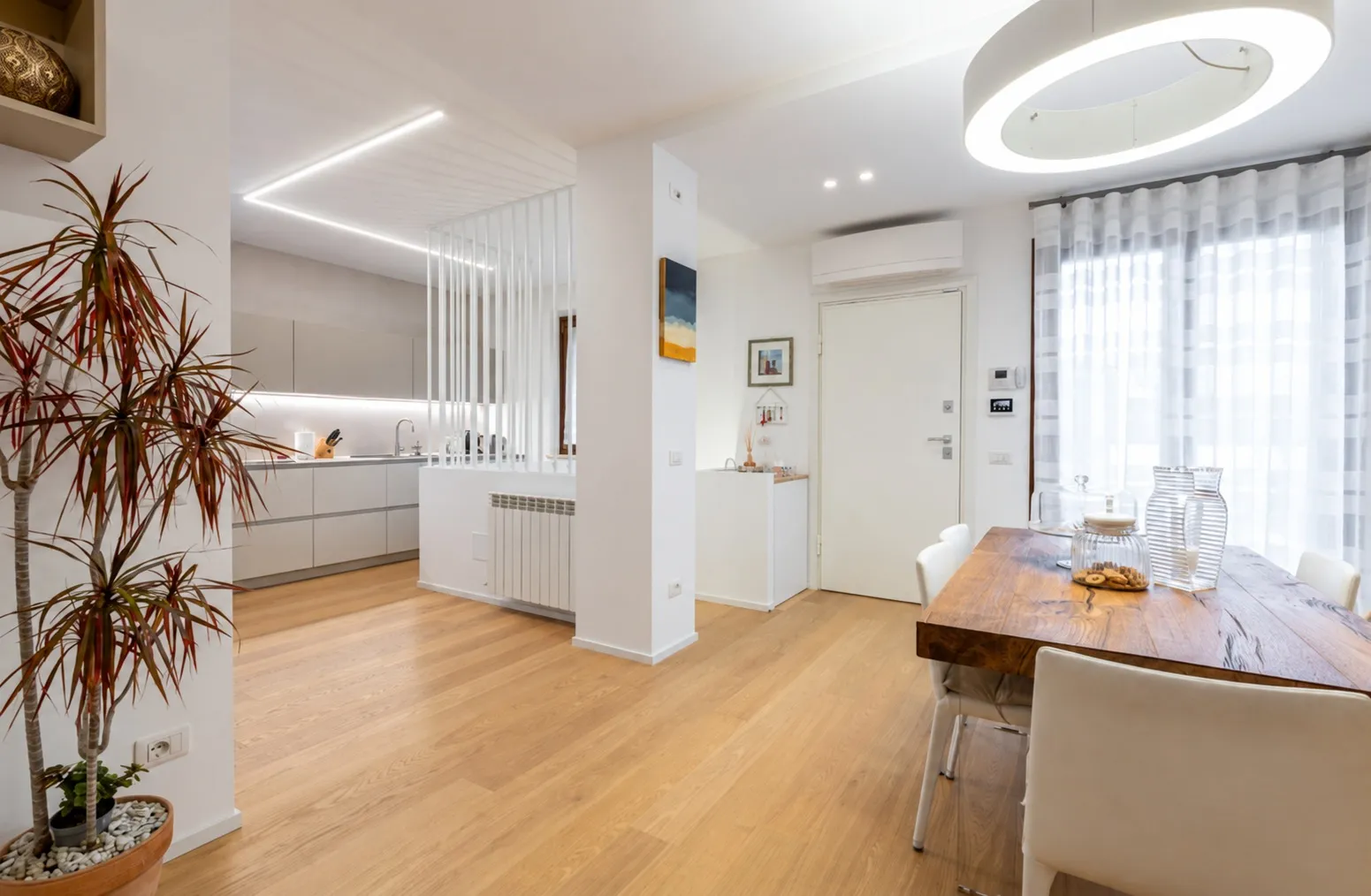 Cucina a vista separata da listelli bianchi e parquet in rovere alla Foce